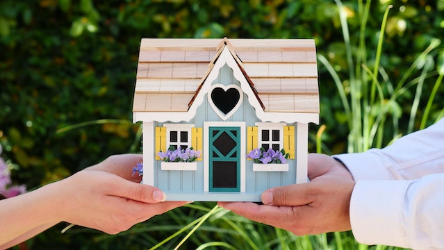 Two people holding a miniature blue house